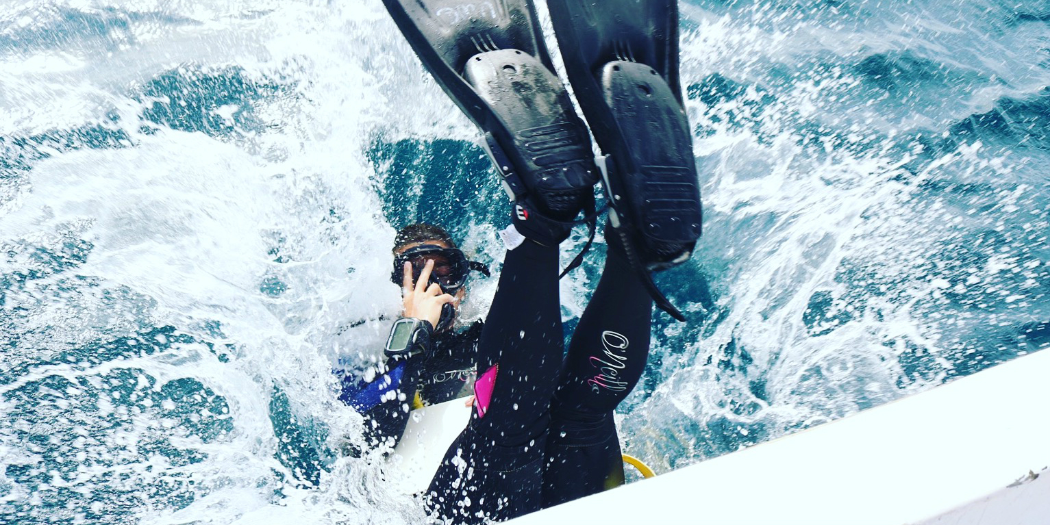 Ein Taucher betritt das Wasser, während er mit seinem PADI Pro Training beschäftigt ist.